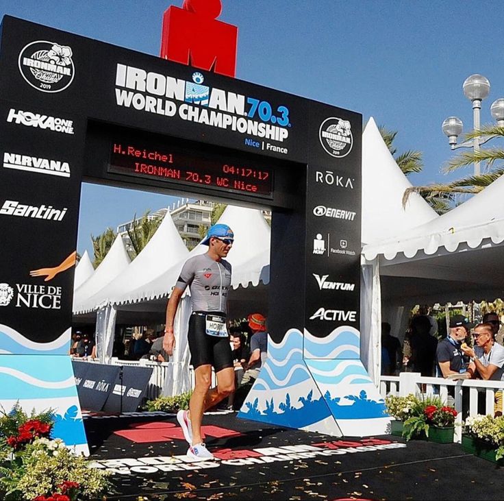 a man is running under an ironman world championship sign at the finish line in front of spectators