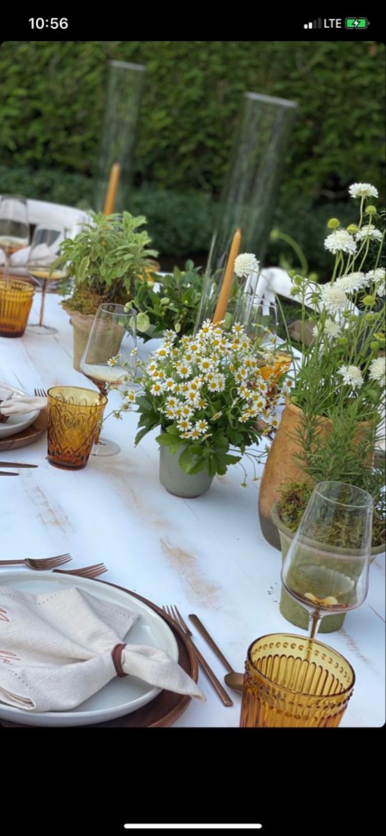 the table is set with plates, silverware and flowers in glass vases on it