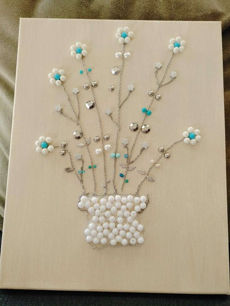 an art piece with beads and flowers on the bottom is displayed in front of a couch