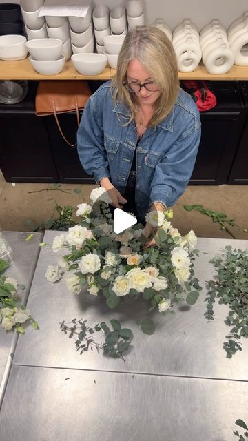 a woman is arranging flowers on a table