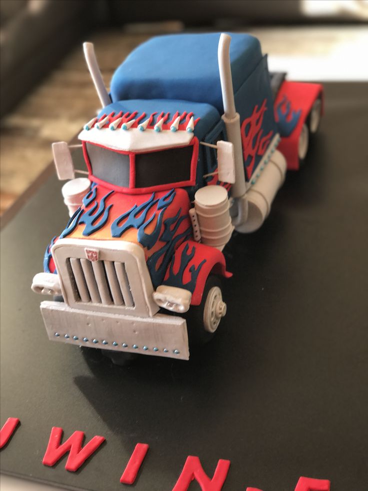 a cake shaped like a semi truck with flames on the front and sides, sitting on top of a table