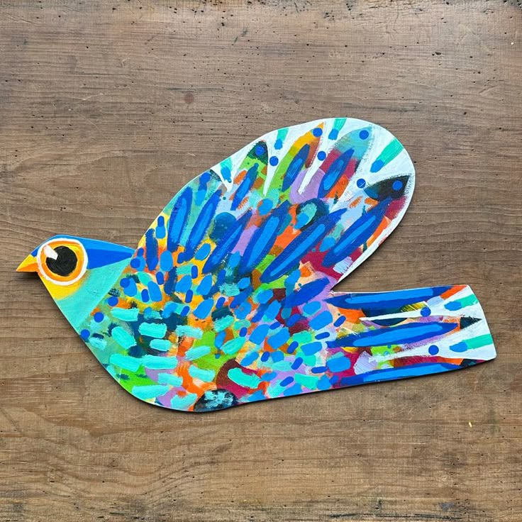 a colorful bird made out of paper on top of a wooden table