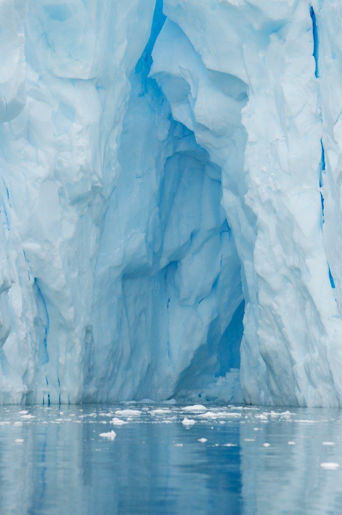 an iceberg is seen from the water in front of it's blue walls