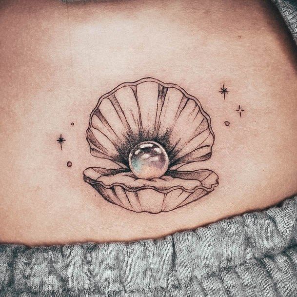 a woman's stomach with a shell tattoo on her belly and an pearl in the center