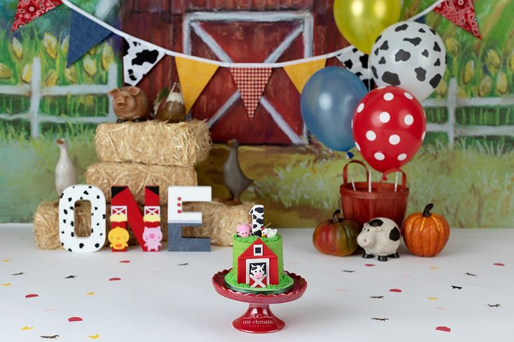 a table topped with lots of balloons next to hay bales and farm animals on top of it