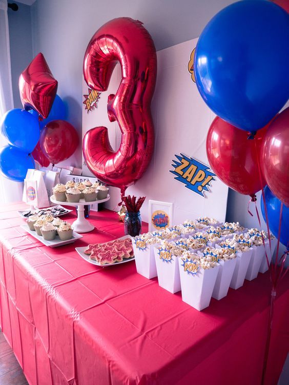 a table topped with lots of cupcakes and balloons