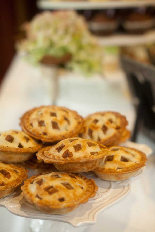 several small pies on a plate sitting on a table with other food items in the background