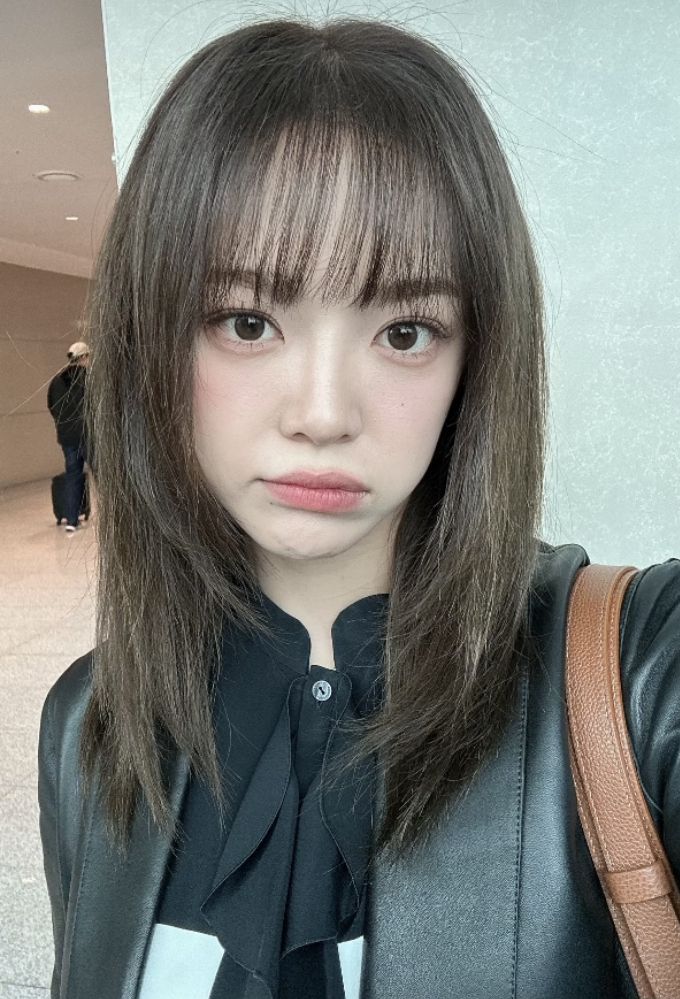 a woman with long hair wearing a black shirt and leather jacket is posing for the camera