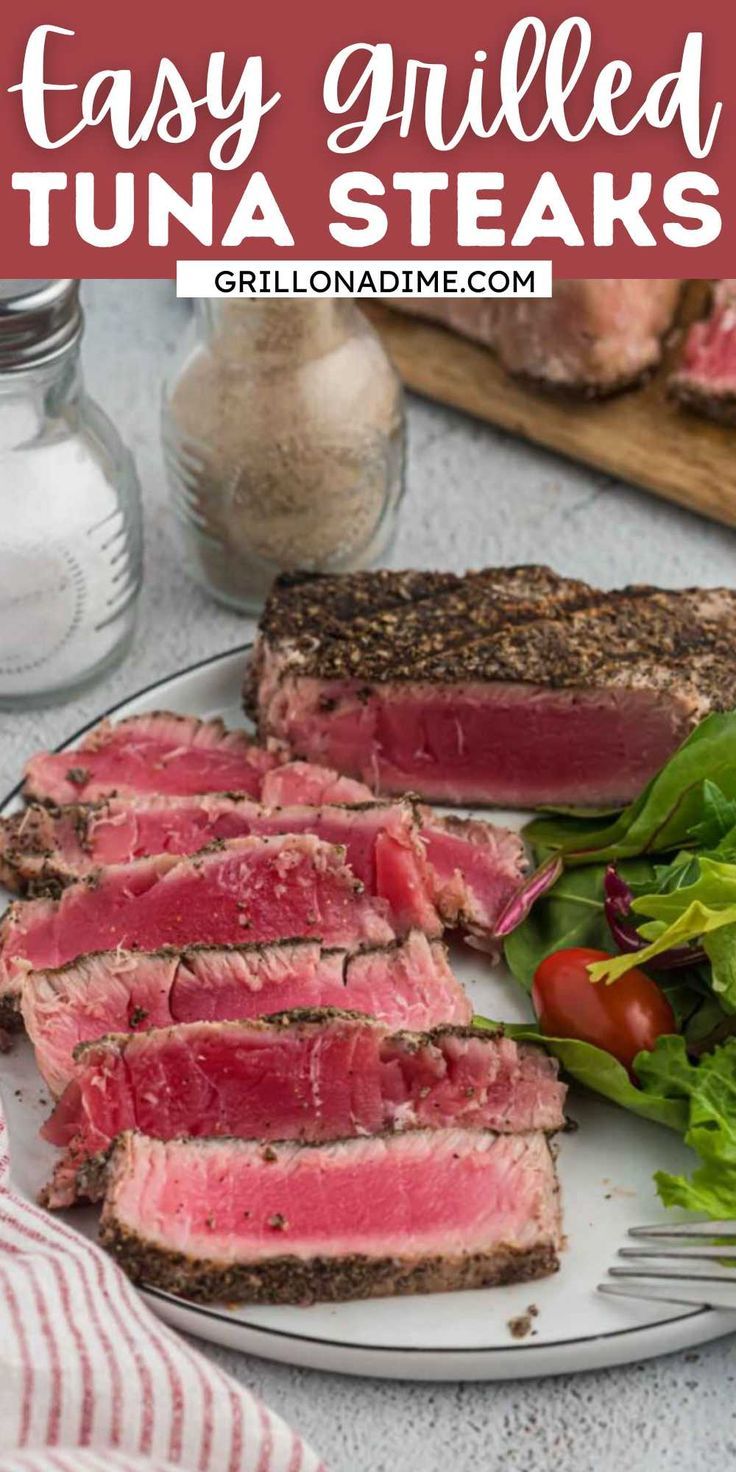 a plate with steak, lettuce and tomatoes on it next to some bread