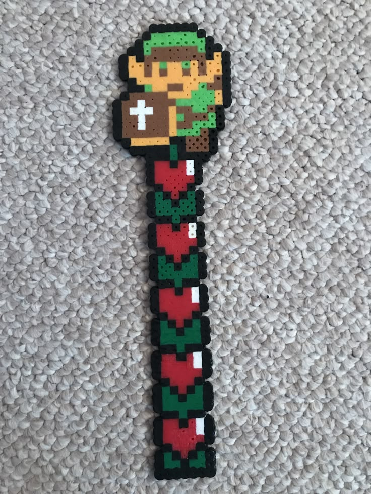 an image of a pixel art keychain on the floor with a video game character hanging from it