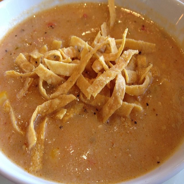 a white bowl filled with soup and some tortilla chips on top of it