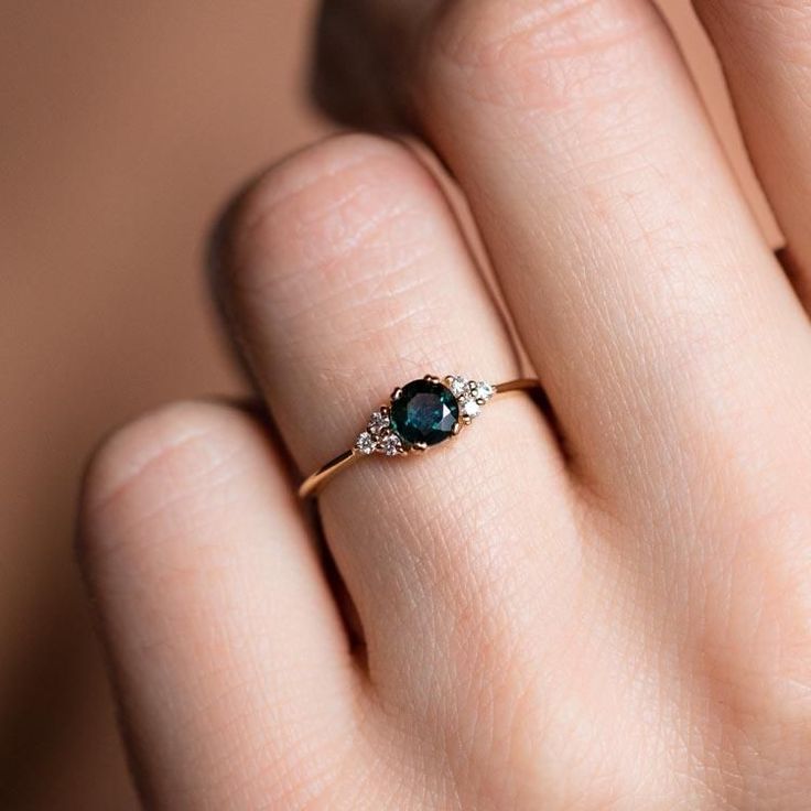 Inspired by the stars, the Lune Ring showcases a captivating teal sapphire, reminiscent of a celestial body, surrounded by a halo of brilliant white diamonds. This unique alternative engagement ring, stunning on either hand, embodies elegance and individuality.  Handmade with care, crafted in 14k solid yellow gold and featuring a 4.5 mm teal sapphire and 0.09 ctw of diamonds.  Allow 4-6 weeks for creation. Sapphire Ring Simple, Rings Sapphire, Parti Sapphire, Green Sapphire Engagement, Alternative Engagement Ring, Blue Green Sapphires, Teal Sapphire, Engagement Inspo, Bespoke Engagement Ring