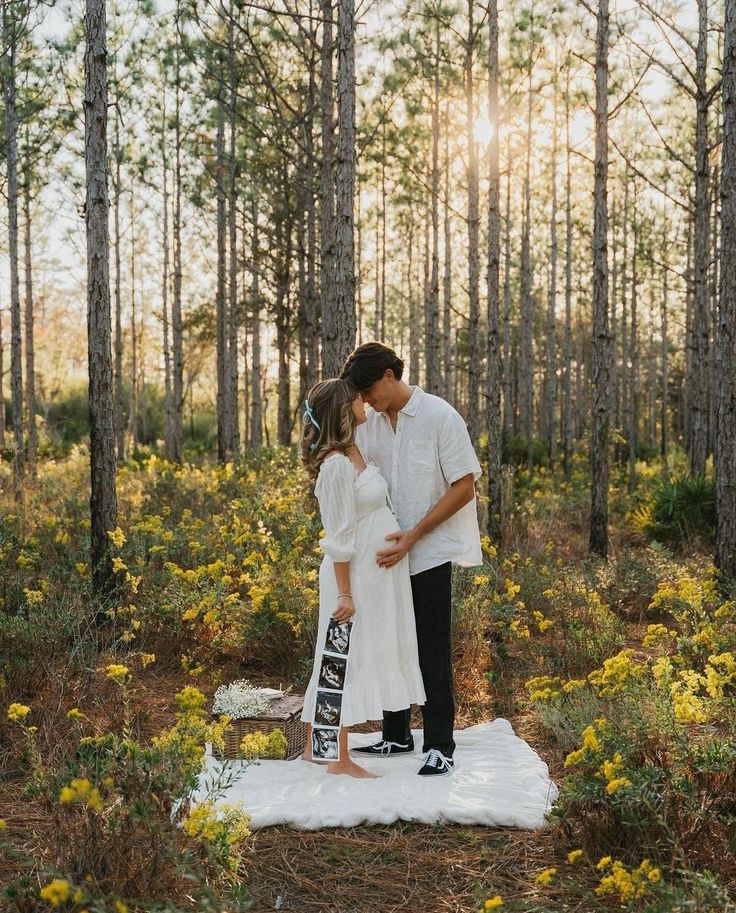 a man and woman standing in the woods with their arms around each other as they kiss