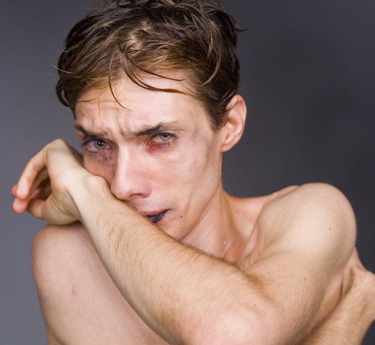 a shirtless man with his hand on his face looking at the camera while posing for a photo