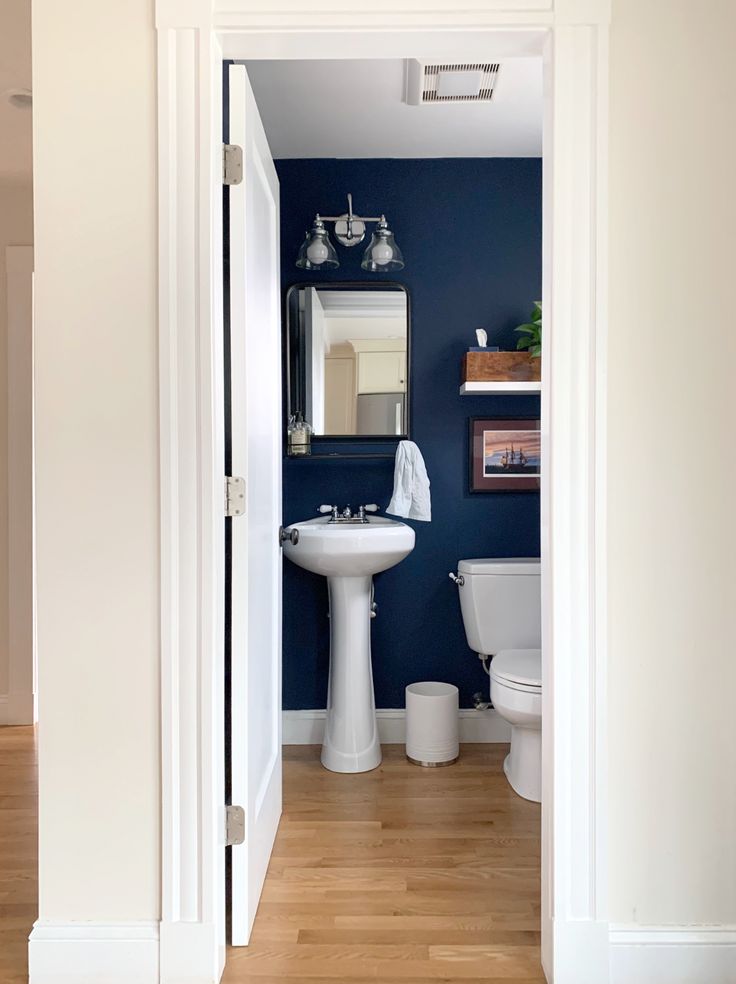 an open door leading to a bathroom with blue walls and white fixtures on the wall