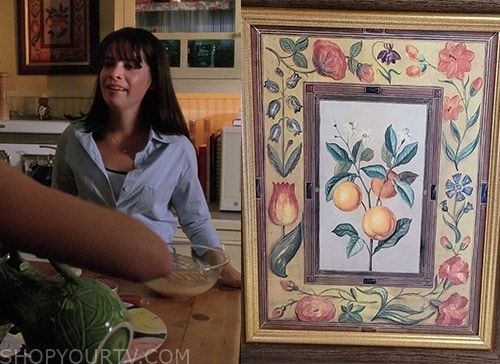 a woman standing in front of a painting on the wall next to a counter top