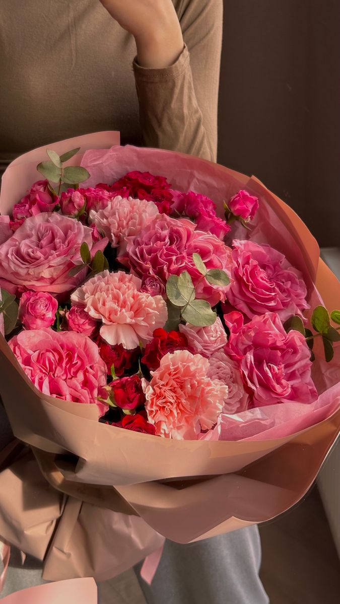 a woman holding a bouquet of pink and red flowers