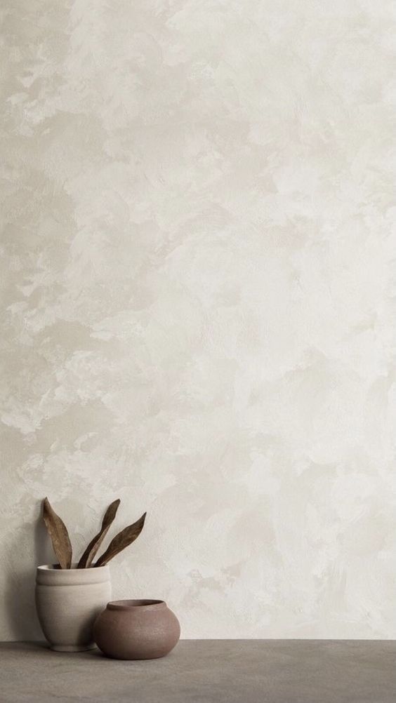 two vases with plants in them sit on a table next to a white wall