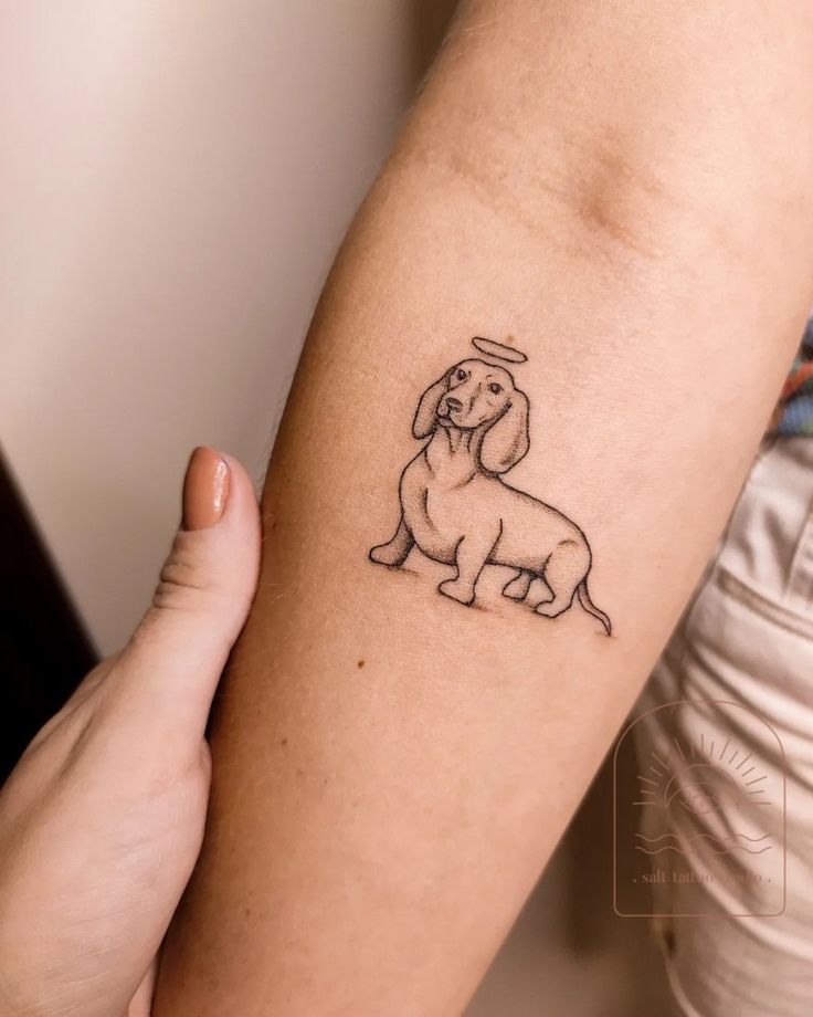 a person holding their arm with a dog tattoo on it's left arm,