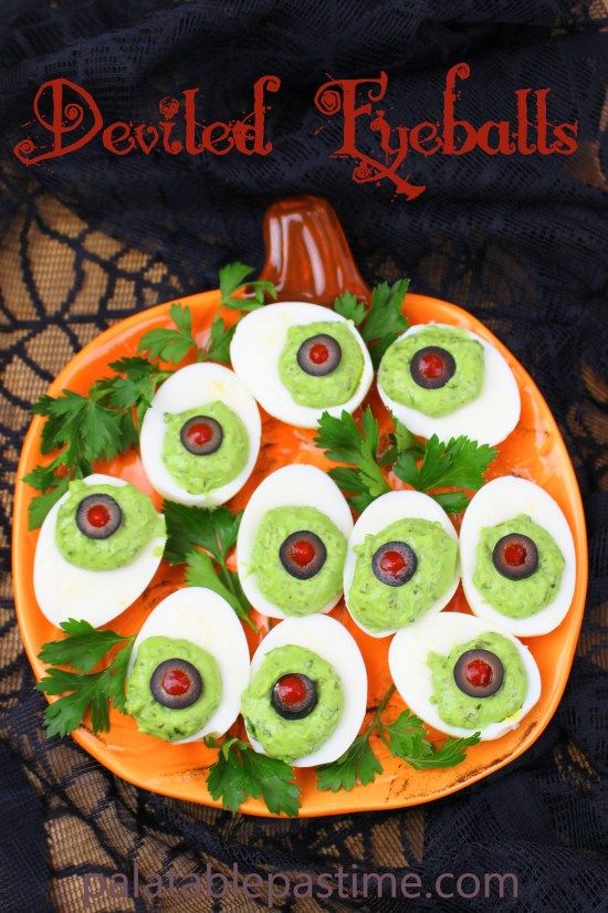 deviled eggs with guacamole and olives on an orange plate