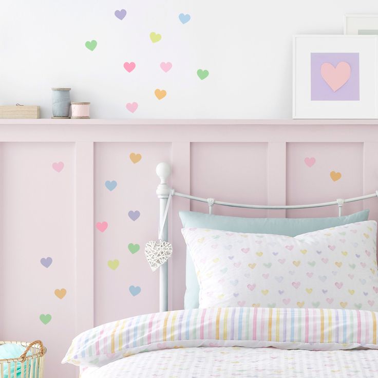 a bed in a bedroom with pink walls and hearts painted on the wall behind it