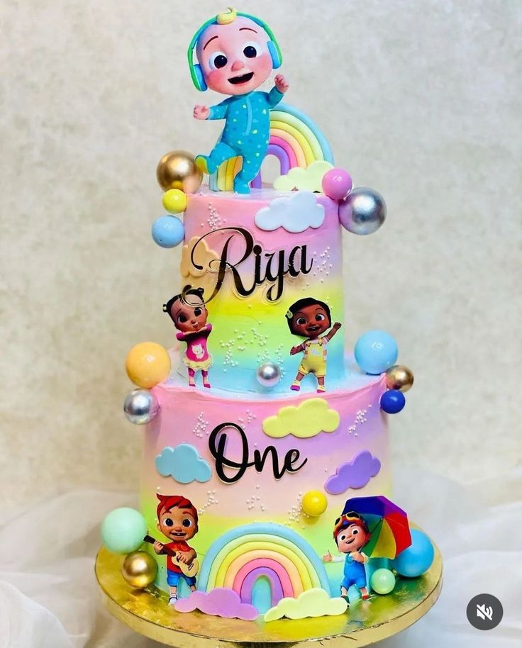 a three tiered cake decorated with cartoon characters and rainbows on the bottom layer