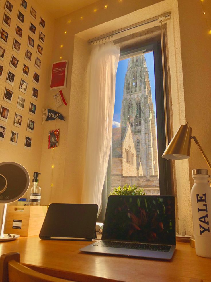 a laptop computer sitting on top of a wooden desk in front of a large window