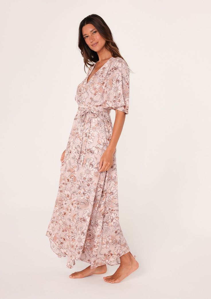 A flowy short flutter sleeve maxi dress in a pink floral print. Floral print Relaxed fit Short flutter sleeves Maxi length Asymmetric hemline V-neckline Elastic waist Self-tie waist belt Lined Bohemian maxi dress Feminine florals add a pretty touch to this classic boho maxi dress. With short flutter sleeves, a flattering v-neckline, and a waist-defining tie belt. The unique asymmetric hemline adds a sweeping touch to the long flowy skirt. Model is 5'9, wearing a size S.Style: I-73347WL-SKF-CG Pink Midi Dress With Tie Waist And Short Sleeves, Feminine Belted Maxi Dress For Summer, Summer Pink Maxi Dress With Kimono Sleeves, Pink Maxi Dress With Floral Print And Surplice Neckline, Pink Maxi Dress With Kimono Sleeves For Summer, Flowy Floral Maxi Dress With Surplice Neckline, Feminine Belted Maxi Dress, Casual Maxi Dress With Floral Print And Kimono Sleeves, Feminine Floral Print Maxi Dress With Surplice Neckline