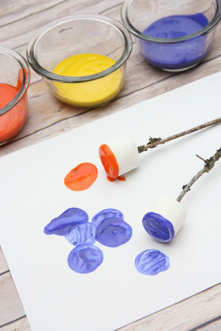 three different colors of paint on paper next to small glass bowls with sticks sticking out of them