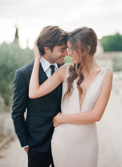 a man in a tuxedo and a woman in a white dress stand close to each other