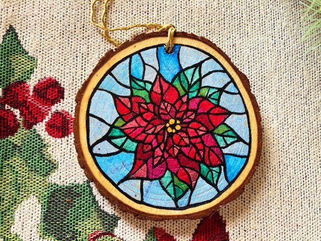 a stained glass ornament with a red flower on it