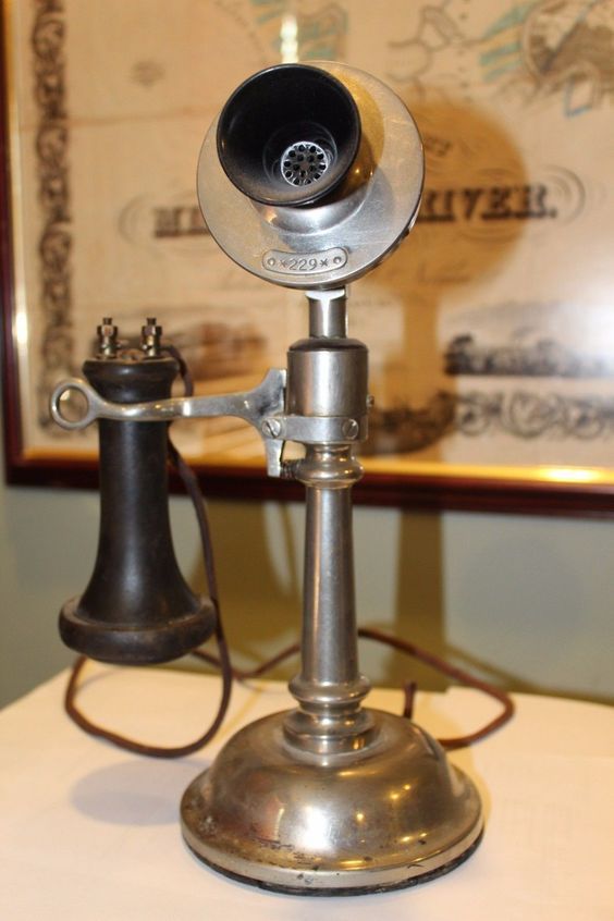 an old fashioned phone is sitting on top of a table next to a wall hanging