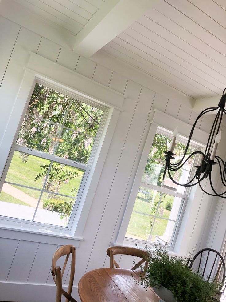 a dining room table with two chairs and a chandelier hanging from the ceiling