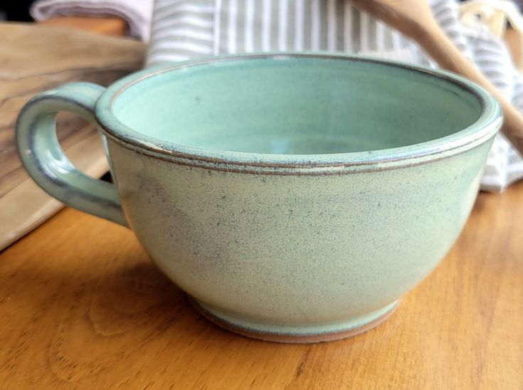 a blue bowl sitting on top of a wooden table next to a knife and spoon