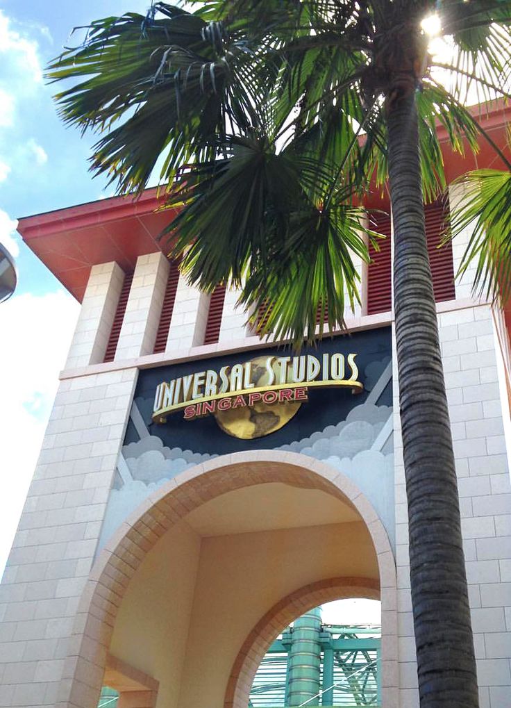 the entrance to universal studios with palm tree in foreground and blue sky behind it