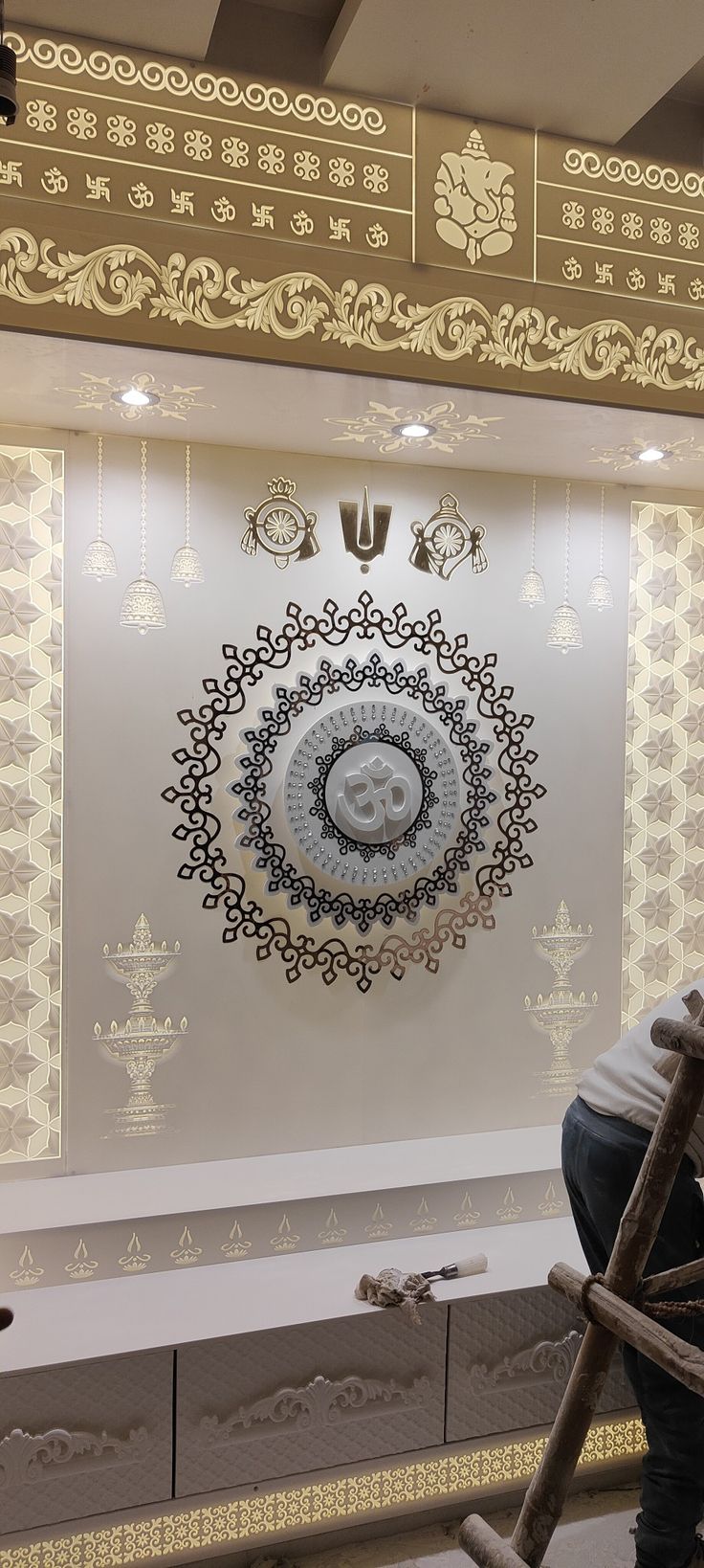 a man sitting on top of a ladder in front of a wall with an intricate design