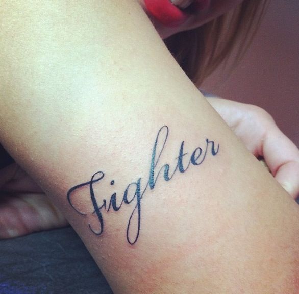 a woman's arm with the word fighter tattooed on her left arm and writing below it