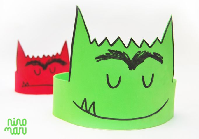 two paper crowns with faces drawn on them, one is green and the other is red