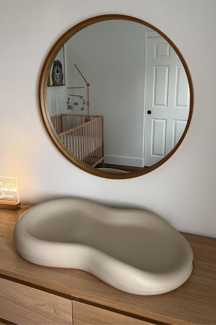 a large oval mirror on the wall above a dresser