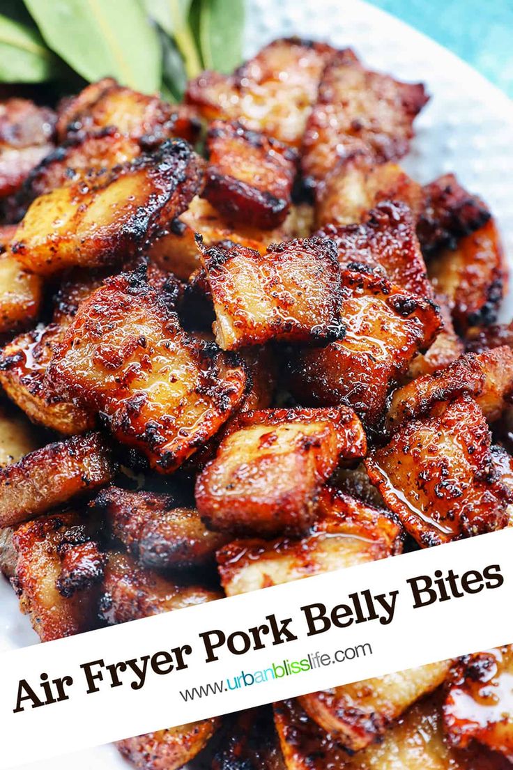 air fryer pork belly bites on a white plate with green leaves in the background