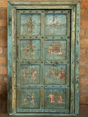 an old green painted wooden door with horses and people on the doors, against a brick wall