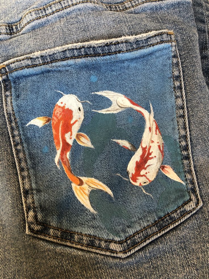 a pair of jeans with gold fish painted on the back pocket and bottom side pockets