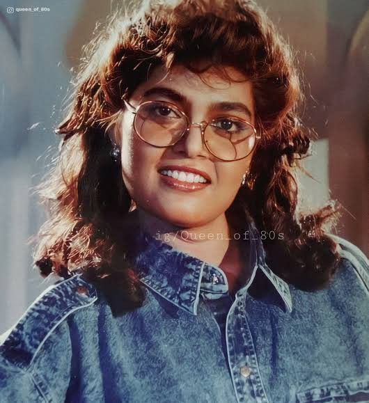 an old photo of a woman wearing glasses and denim shirt with her hair pulled back