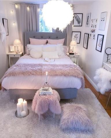 a bedroom decorated in white and pink with fur rugs on the floor, candles lit up