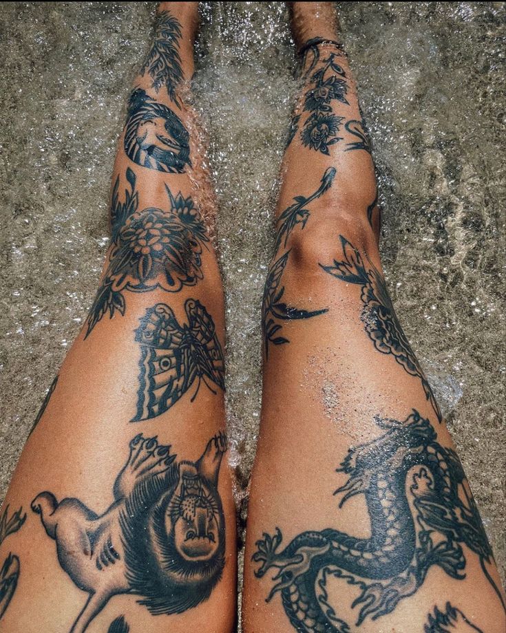 a person with tattoos on their legs standing in the water