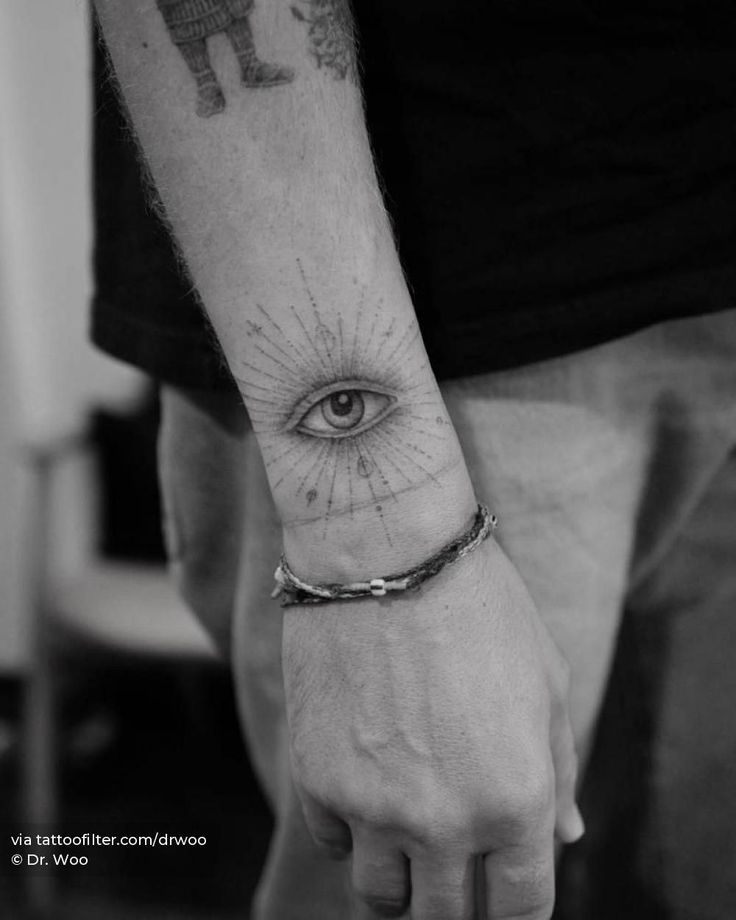 a man's arm with an eye tattoo on it and a chain around the wrist