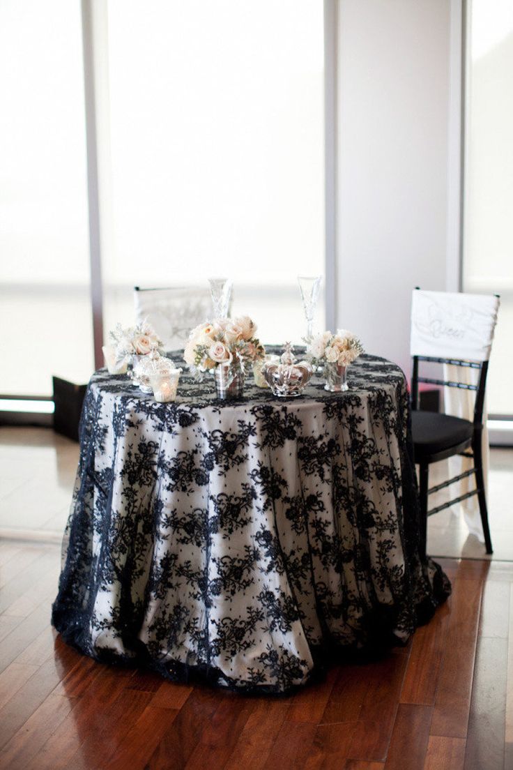 a black and white table cloth on top of a round table with chairs around it