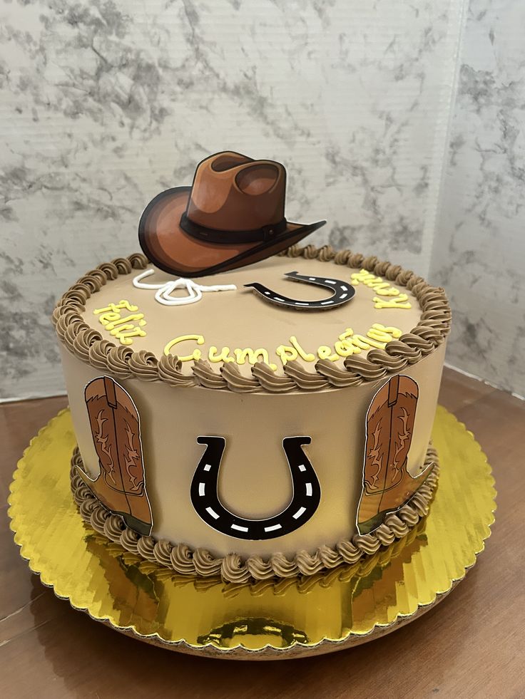 a birthday cake with a cowboy hat and horseshoes on the top is sitting on a yellow plate