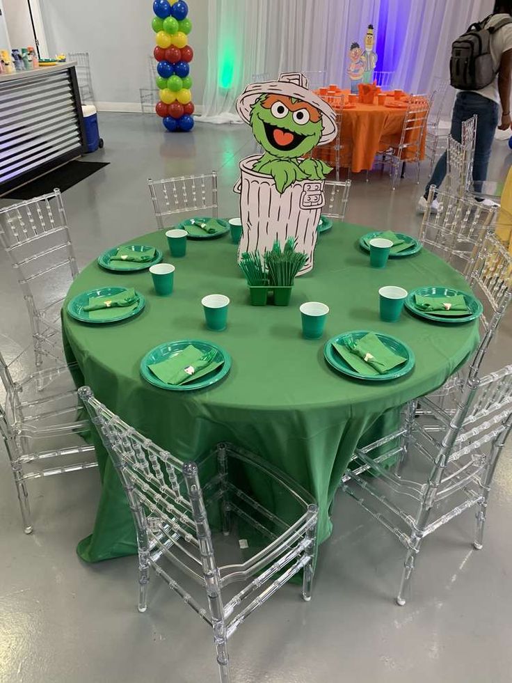 a green table topped with plates and cups next to a cut out of an animal