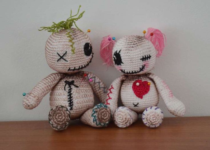 two crocheted teddy bears sitting next to each other on top of a wooden table